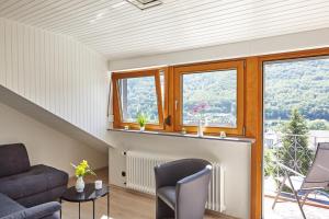 een woonkamer met een bank, een open haard en ramen bij Ferienwohnung Mendgen mit Panoramablick in Bernkastel-Kues