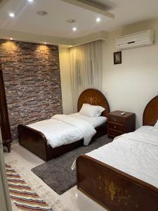 1 dormitorio con 2 camas y pared de ladrillo en Superb & comfy 3BDR apartment with outstanding view شقة فندقية فاخرة فيو رائع للمطار, en El Cairo