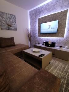ein Wohnzimmer mit einem Sofa und einem Fernseher an der Wand in der Unterkunft JM Apartman in Čačak