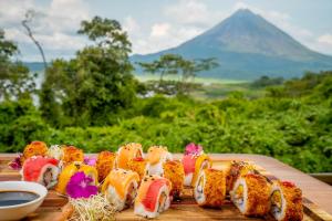 a group of sushi on a wooden table with a mountain at Villas Paradise in El Castillo de La Fortuna