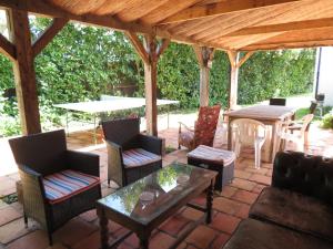 a patio with chairs and tables and a wooden pergola at The Barn, Norwich in Norwich