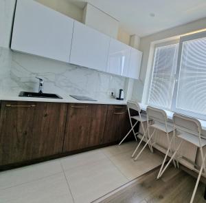 - une cuisine avec des comptoirs blancs et des armoires en bois dans l'établissement Vanilės apartamentai, à Klaipėda