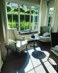 un soggiorno con sedie, tavolo e finestre di Maison Juliette a Lembeke