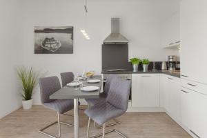 ハイリゲンハーフェンにあるFischers Friendの白いキャビネット、テーブルと椅子付きのキッチンが備わります。