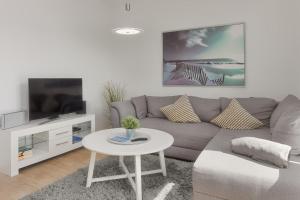 a living room with a gray couch and a white table at Fischers Friend in Heiligenhafen