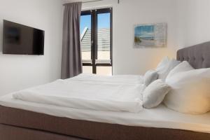 a bed with white sheets and pillows and a television at Fischers Friend in Heiligenhafen