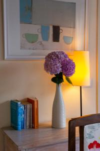 a vase of purple flowers on a table next to a lamp at Cascina del Forte in Torre Pellice