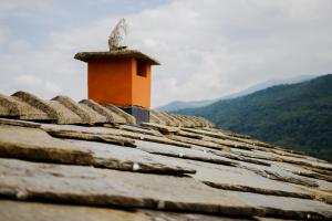 a chimney on top of a roof with mountains in the background at Cascina del Forte in Torre Pellice