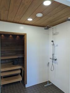 a bathroom with a shower with a wooden ceiling at Kartanonrinteen Amanda in Teijo