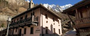 um edifício com uma varanda com montanhas ao fundo em Locanda La Brenva - Estella Hotel Collection em Courmayeur