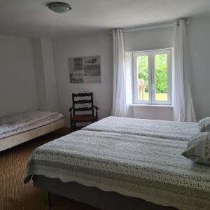 a bedroom with a bed and a window and a chair at La Balnière Normande in Hambye