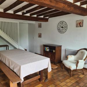 a bedroom with a bed and a chair and a clock at La Balnière Normande in Hambye