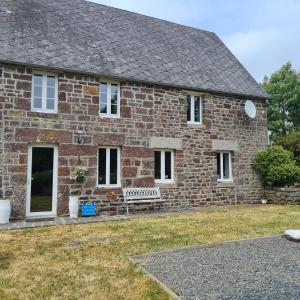 uma casa de tijolos com um banco à frente em La Balnière Normande em Hambye