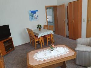 - un salon avec une table, des chaises et une télévision dans l'établissement Ferienwohnung 1, unten, à Bad Wilsnack