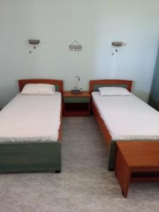 two beds in a room with two tables at Panorama Rooms in Kyllini