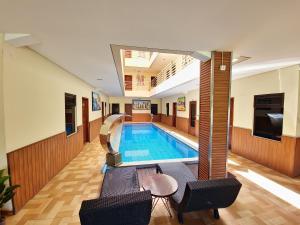 a pool in the middle of a building with chairs at Caroline Guest House in Canggu