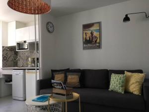 - un salon avec un canapé noir et une table dans l'établissement APPARTEMENT-JARDINET 300 m plage ST PALAIS SUR MER, à Saint-Palais-sur-Mer
