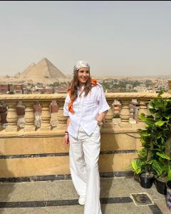 Crowne Pyramids view inn في القاهرة: امرأة تقف أمام الاهرامات