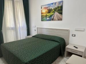 a bedroom with a green bed and a picture on the wall at Hotel Barbarossa in Porto Azzurro
