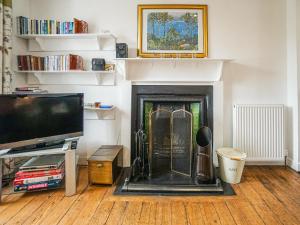 uma sala de estar com lareira e uma televisão de ecrã plano em The Rennie Mackintosh Retreat em Comrie