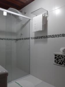 una doccia con porta in vetro in bagno di Pousada Canoa Caiçara Ilhabela a Ilhabela