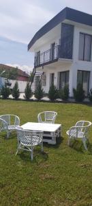 a group of white benches sitting in the grass in front of a house at Accent House in Deva