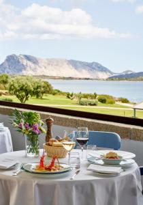 a table with plates of food and glasses of wine at Due Lune Puntaldia Resort & Golf in San Teodoro