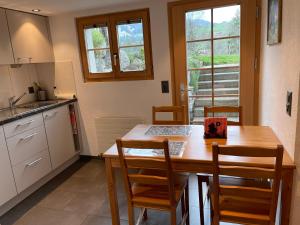 eine Küche mit einem Holztisch und Stühlen sowie einem Tisch und einem Fenster in der Unterkunft Alpenchalet Spiher Gstaad Ferienwohnung im Parterre in Gstaad