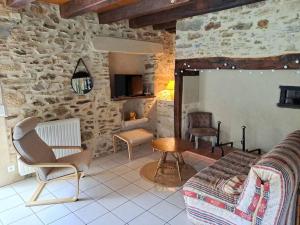 uma sala de estar cheia de mobiliário e uma parede de pedra em Maison Landes - Gite 4 personnes em Latouille-Lentillac