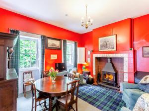 a living room with red walls and a table and a fireplace at The Ivy Wing in Slickly