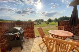 een grill op een patio met een tafel en stoelen bij Tiny Haus Straußenblick 2 in Bad Fallingbostel