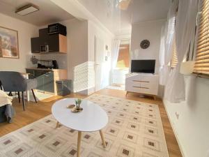 ein Wohnzimmer mit einem weißen Tisch und eine Küche in der Unterkunft Tiny Haus Straußenblick 2 in Bad Fallingbostel