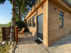 eine Holzhütte mit einer großen Tür neben einem Baum in der Unterkunft Tiny Haus Straußenblick 2 in Bad Fallingbostel