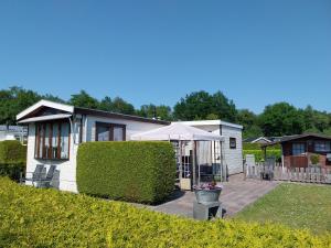 een wit huis met een paraplu in een tuin bij Chalet in Drenthe te huur aan de rand van het bos Drents Friese Wold, veel PRIVACY en RUST in Hoogersmilde