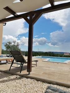 um pátio com uma cadeira e uma piscina em Villa Scolopax rusticola Skradin with heated pool em Skradin