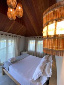 1 dormitorio con 1 cama blanca y 2 lámparas de araña en Tatadise, en Tatajuba