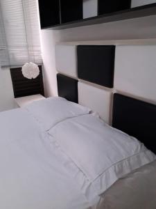 a white bed with a black and white headboard at Kit no Lago Norte CA 02 in Brasilia