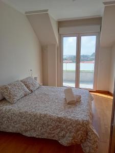 a bedroom with a bed and a large window at Apartamento Vistas a ensenada in Meaño