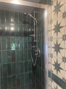 a shower in a bathroom with green tiled walls at Railway cottage Annascaul in Annascaul