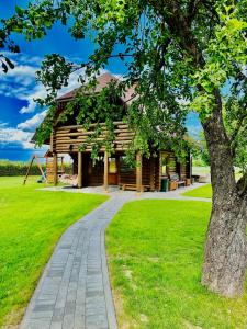 a log cabin in a park with a tree at Brīvdienu māja Odumiņi in Leimaņi