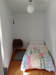 a bedroom with a bed and a chair at A casiña de Vilaxoan in Vilagarcia de Arousa