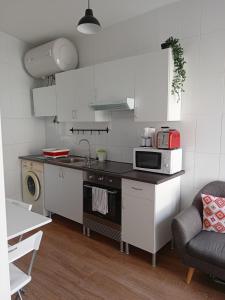a small kitchen with a stove and a microwave at A casiña de Vilaxoan in Vilagarcia de Arousa
