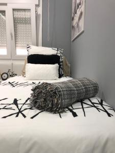 Una cama con una manta blanca y negra. en Apartamento Victorio Las Canteras, en Las Palmas de Gran Canaria