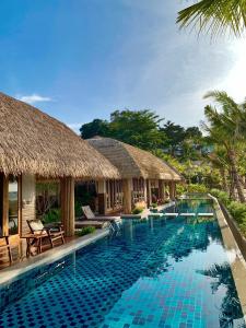 a pool at a resort with thatched huts at Bulow Casa Grand View Resort in Ko Lipe