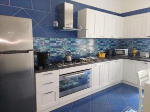 a kitchen with white cabinets and blue tiles at Blue's House in Atrani