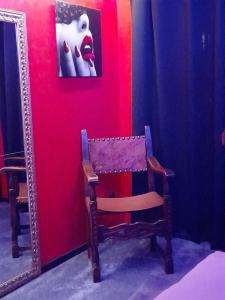a chair in front of a red wall with a mirror at LOVE ROOM Le rouge et noir in Barr