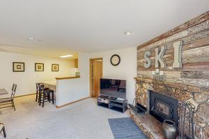 a living room with a stone fireplace and a table at Buffalo Village Condo & Treetop Hideaway in Silverthorne