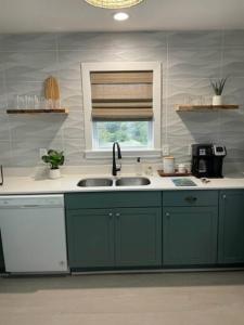 a kitchen with green cabinets and a sink and a window at The Lost Loggerhead- OBX Ocean view Beach House in Avon