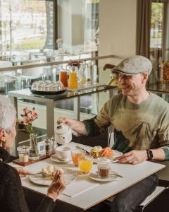 ビルバオにあるホテル ミロの二人の老人がテーブルに座って食べ物を食べている