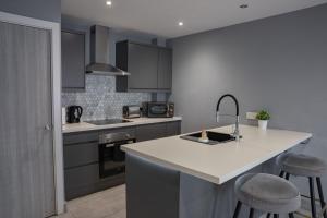 uma cozinha com um lavatório e um balcão com bancos em #4 Reed Street Apartment Hull City Centre nr Connexin Live em Hull